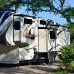 Image of white fifth wheel connected to campground utilities